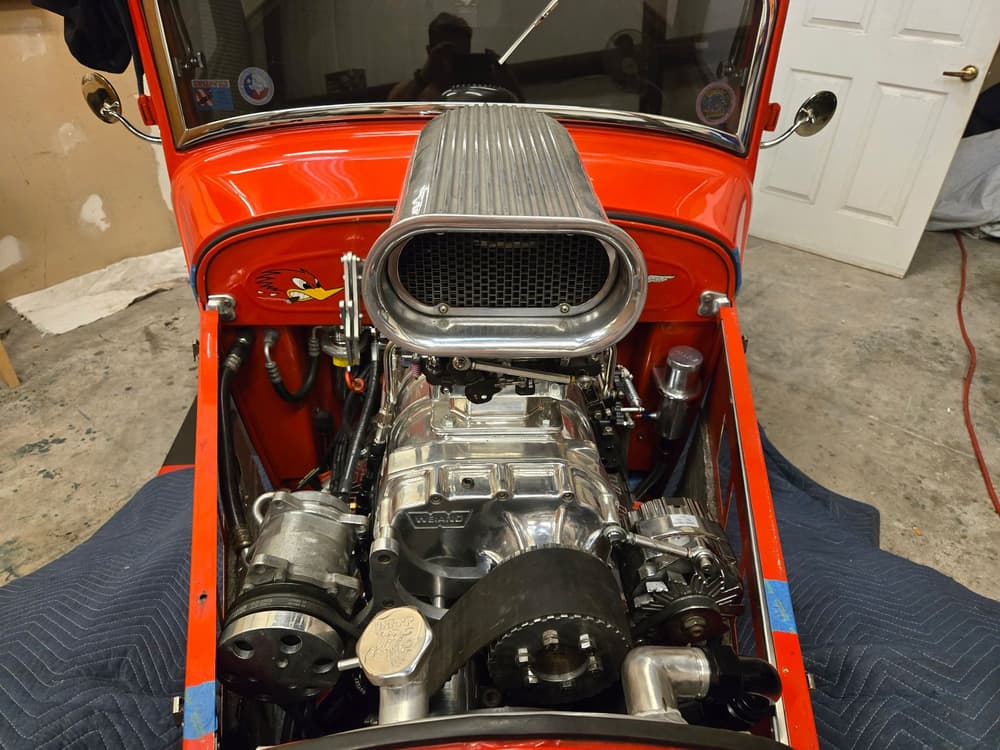 Blown supercharged small-block V8 with a polished blower in an orange hot rod.